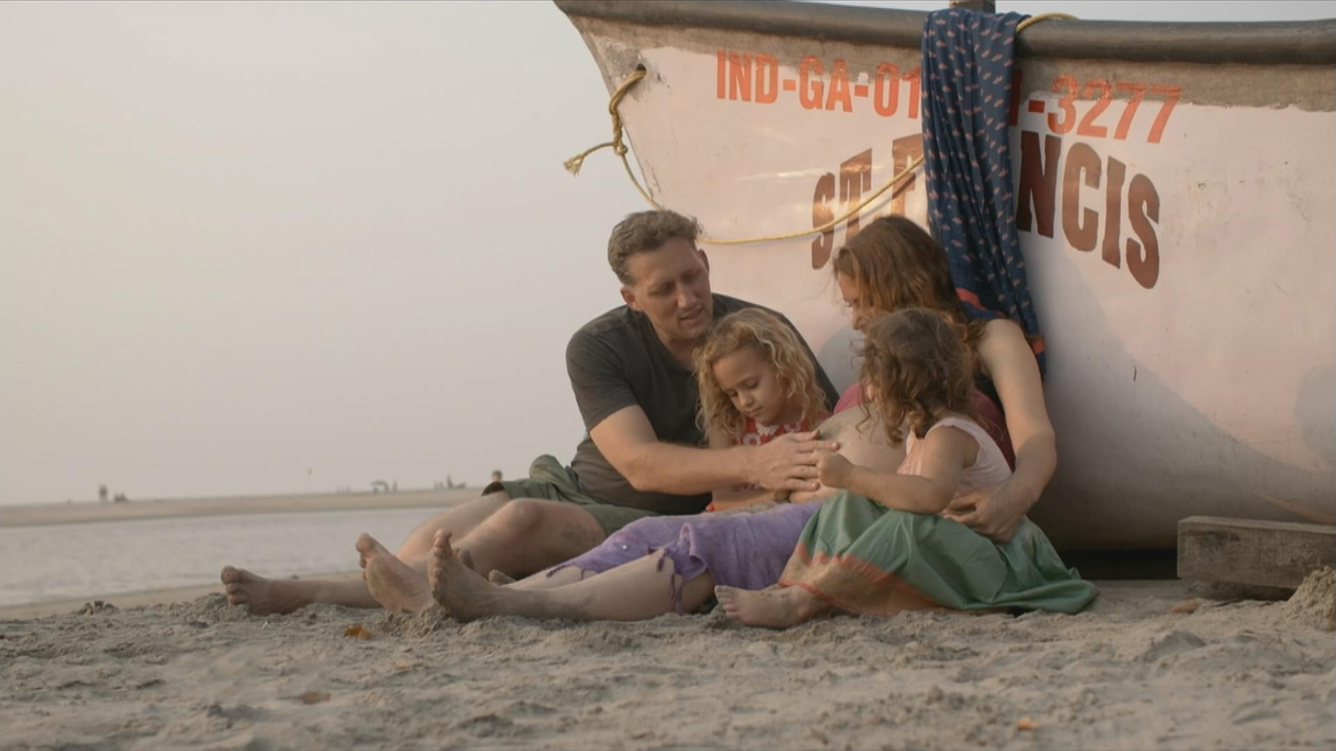 Familie sitzt am Strand