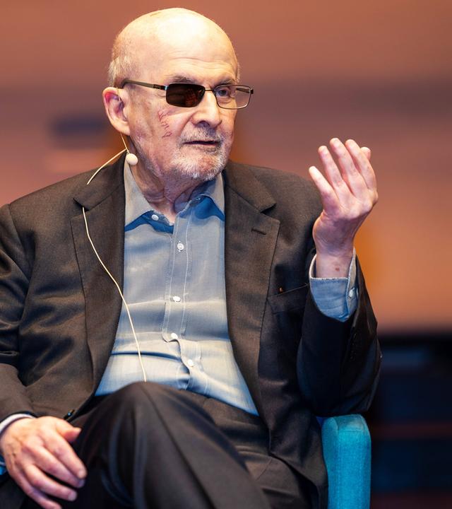 Ein älterer Mann mit graumeliertem Bart und einem geschwärzten Brillenglas.