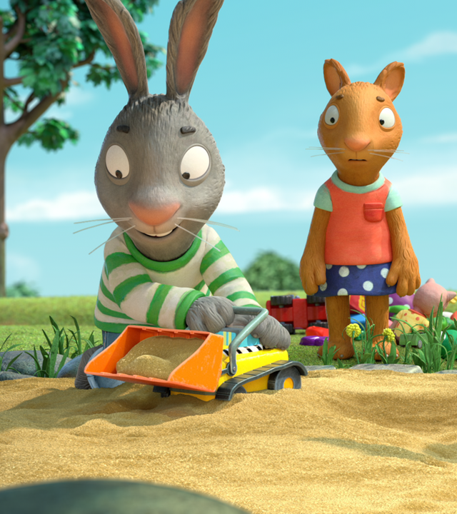 Pip spielt im Sandkasten begeistert mit Zacs Bagger. Zac sitzt rechts von ihm und hat eine Schaufel in der Hand. Hinten steht zwischen den beiden Posy. Sie sieht traurig aus.