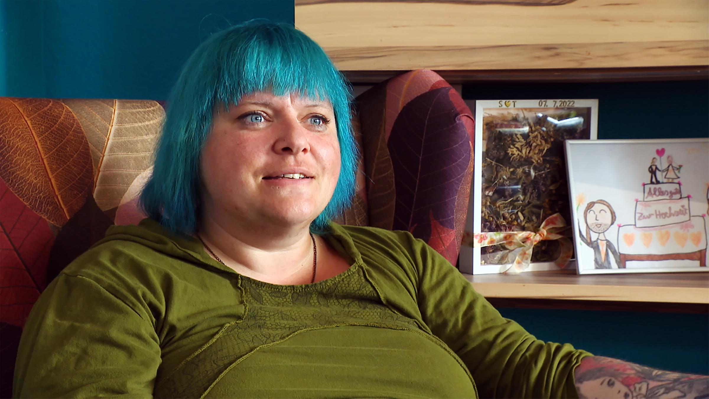 Junge Frau sitzt auf einem Sessel und schaut in die Ferne