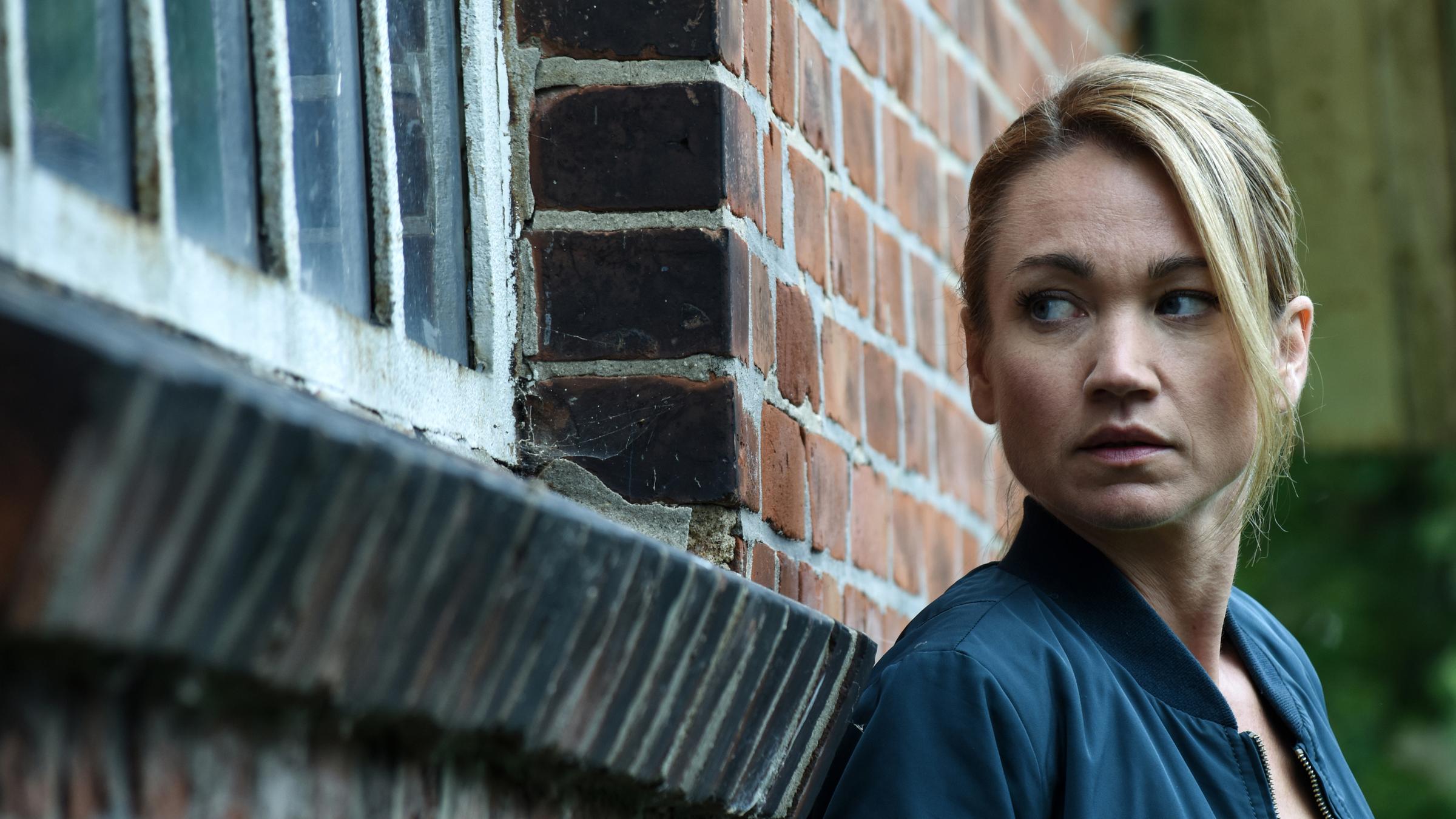 Sarah Kohr: Mord im Alten Land - Drehstart“: Sarah (Lisa Maria Potthoff) steht vor einem Fenster und schaut neugierig hinein.