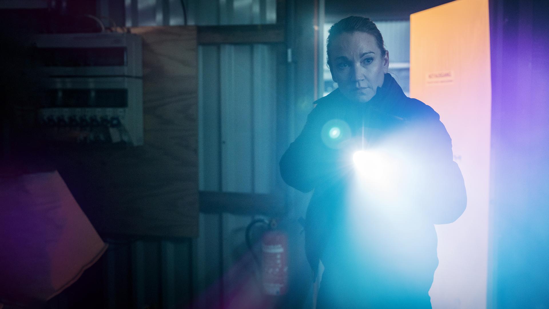 Sarah Kohr (Lisa Maria Potthoff) steht mit einer Taschenlampe in einem dunklen Raum.
