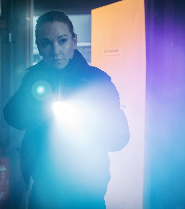 Sarah Kohr (Lisa Maria Potthoff) steht mit einer Taschenlampe in einem dunklen Raum.