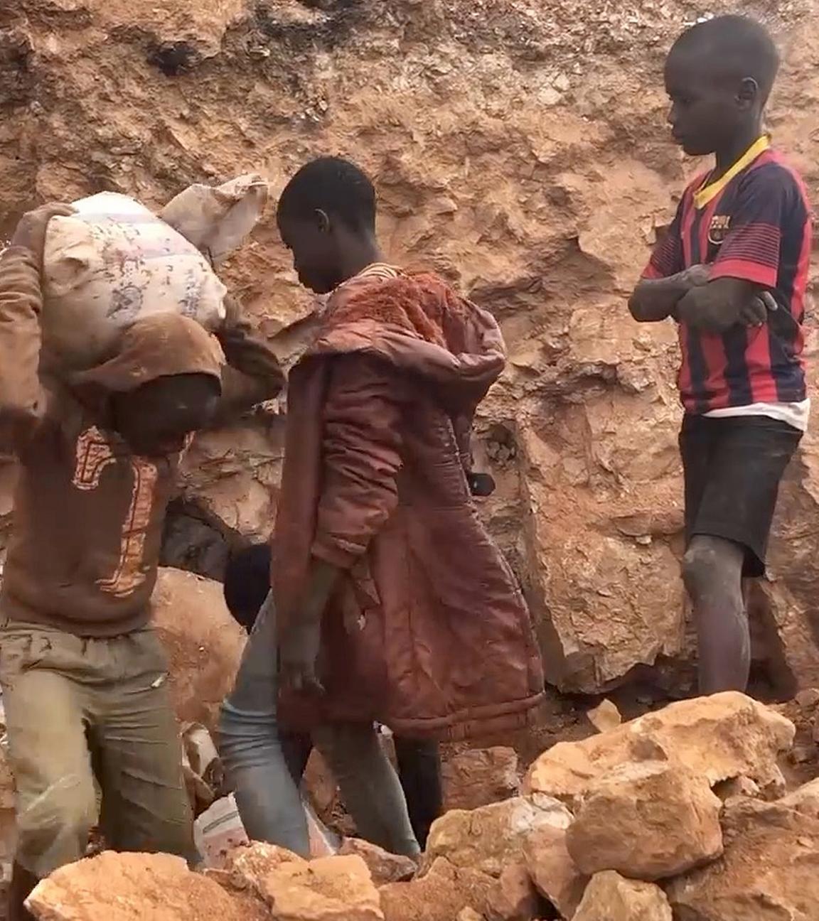Vier Jungs aus dem Kongo tragen Kobalt aus einem Stollen.