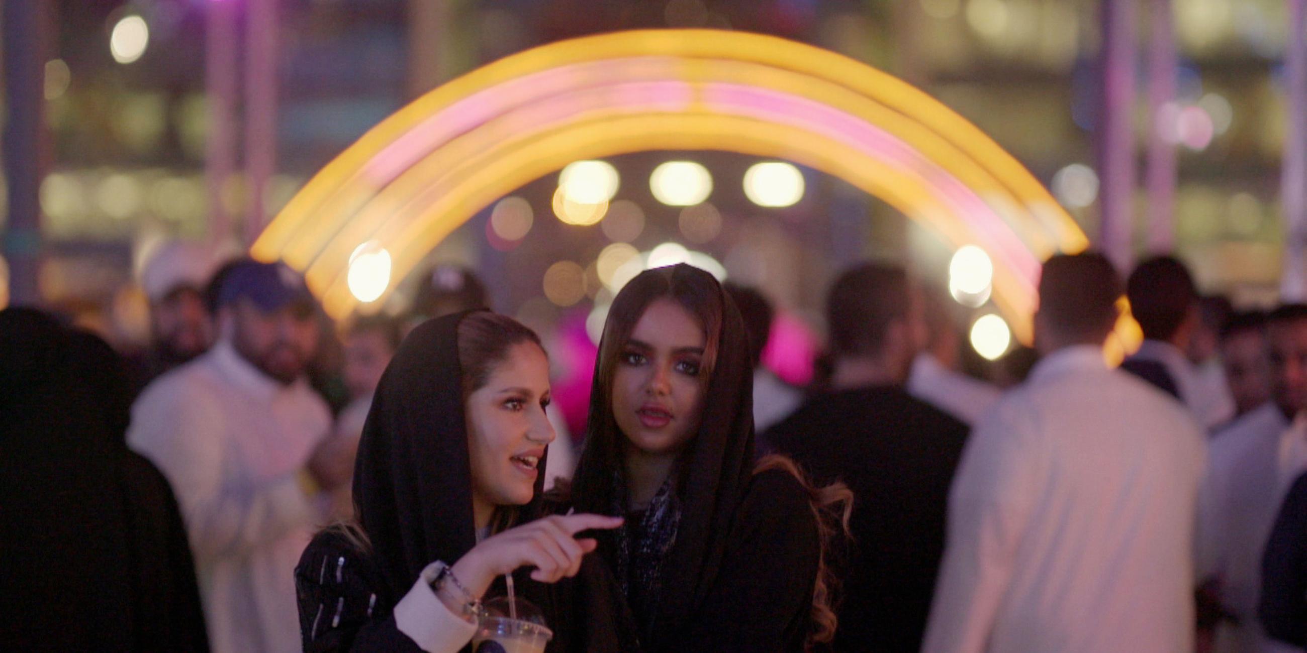 "Saudi Arabien - Öl, Tradition und Zukunft: Neue Freiheit": Abendaufnahme: Geschminkte saudische Frauen vor einer Menschenmenge. Im Hintergrund ein Lichtbogen.