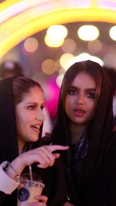 "Saudi Arabien - Öl, Tradition und Zukunft: Neue Freiheit": Abendaufnahme: Geschminkte saudische Frauen vor einer Menschenmenge. Im Hintergrund ein Lichtbogen.