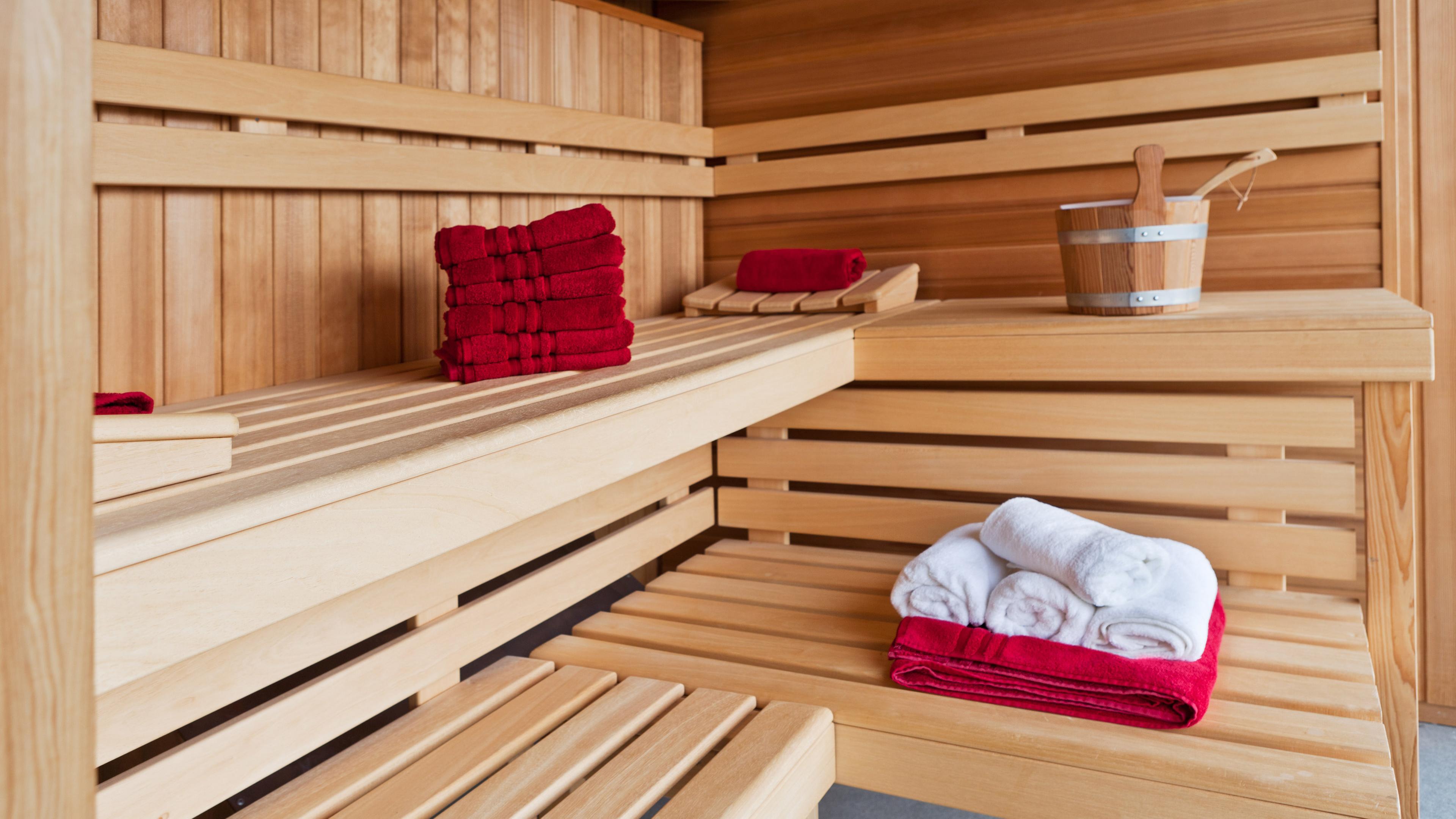 In einer leeren Sauna liegen frische Handtücher und ein Aufgusskübel.
