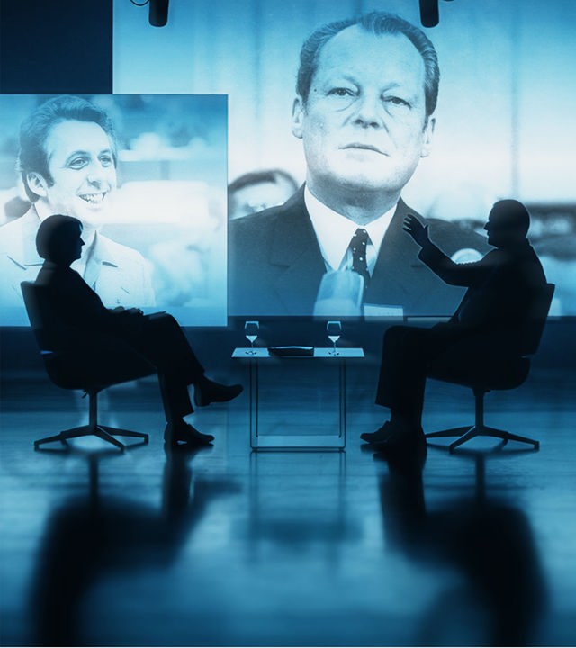 Die Silhouetten von Hans Magnus Enzensberger und Gero von Boehm vor großen blau leuchtenden Portraits