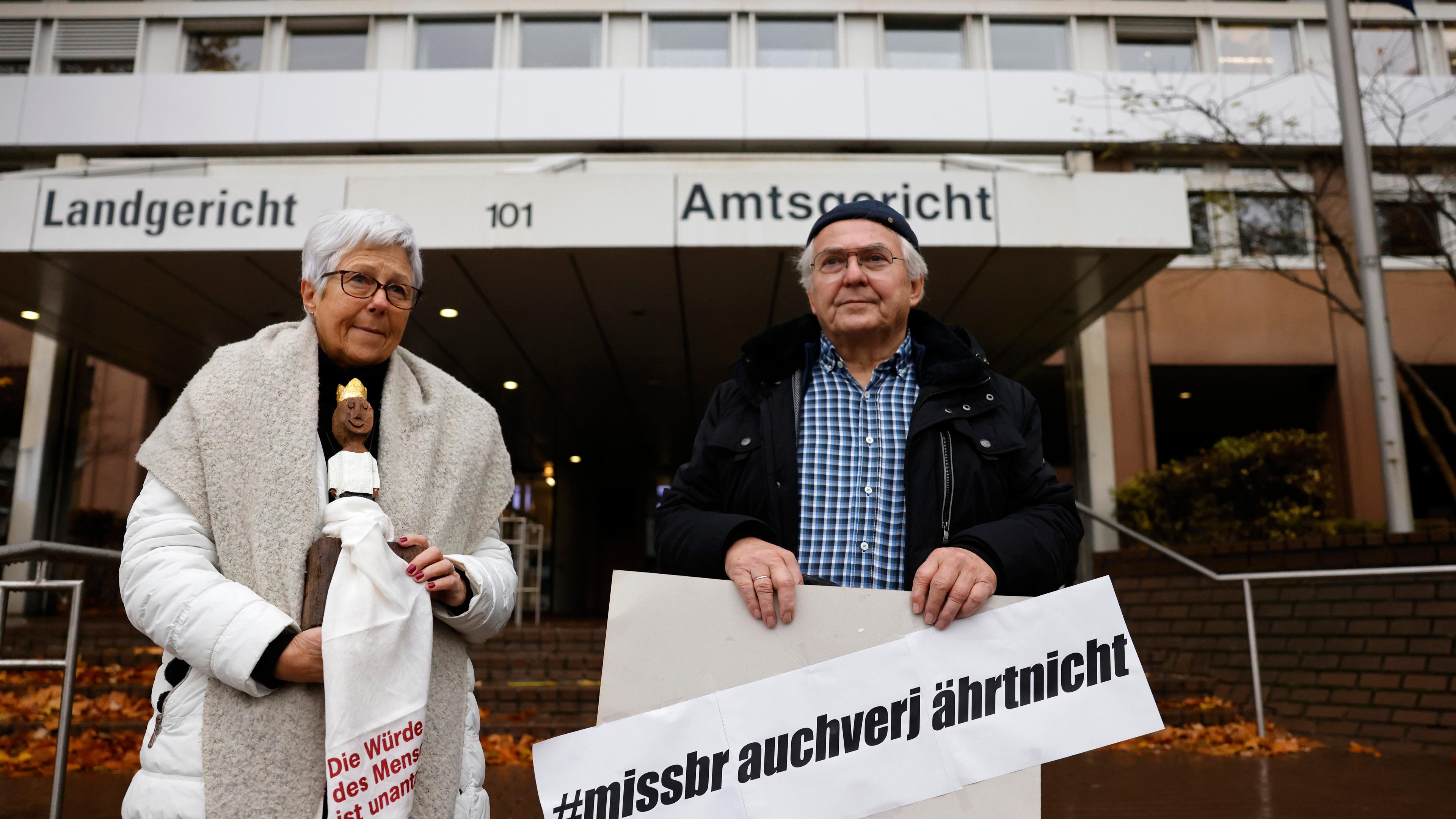 Unterstützer von Kläger Georg Menne stehen vor dem Landgericht Köln und halten ein Plakat mit der Aufschrift: " #missbrauch verjährt nicht."