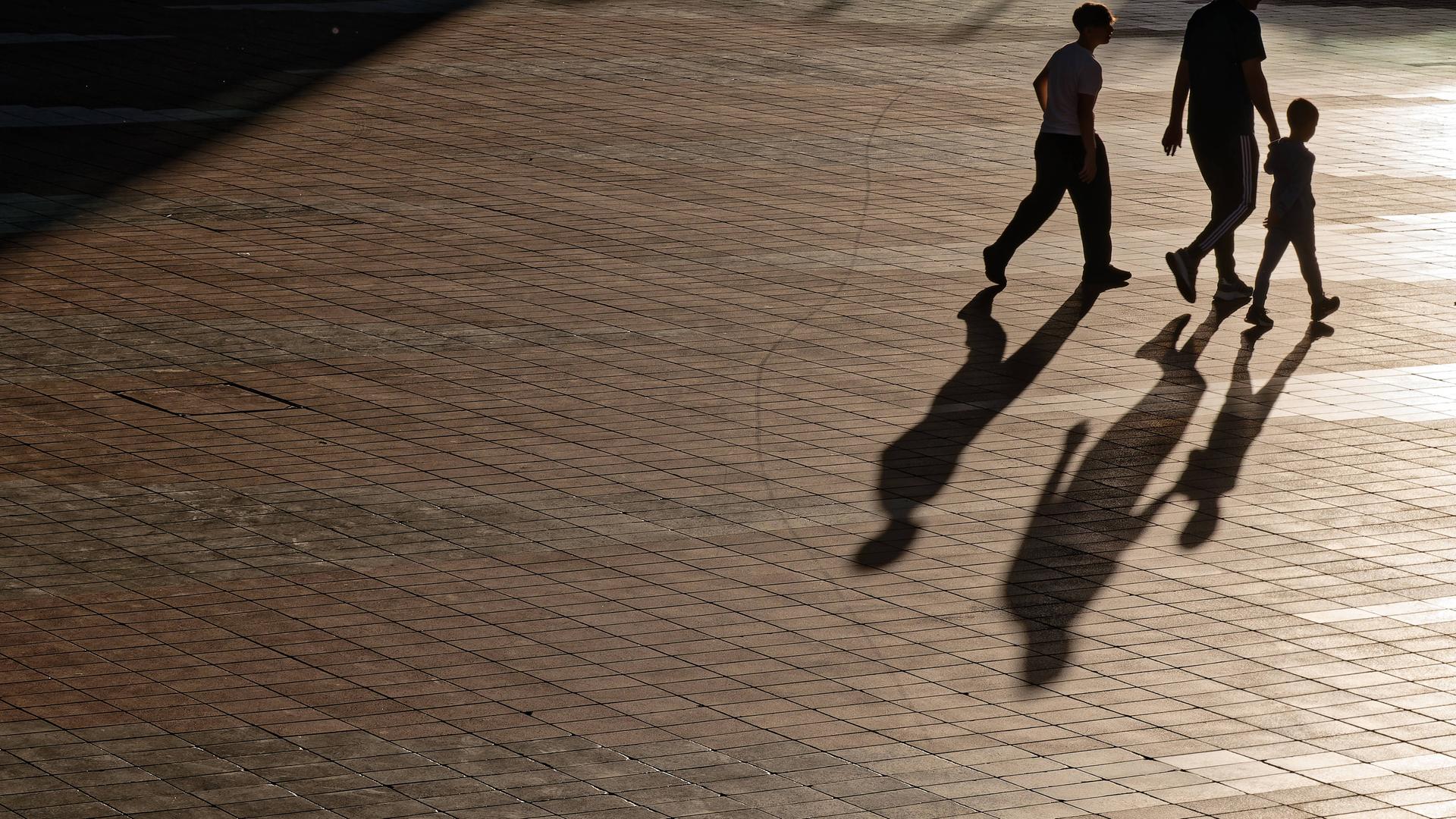Menschen laufen durch die Stadt und werfen Schatten