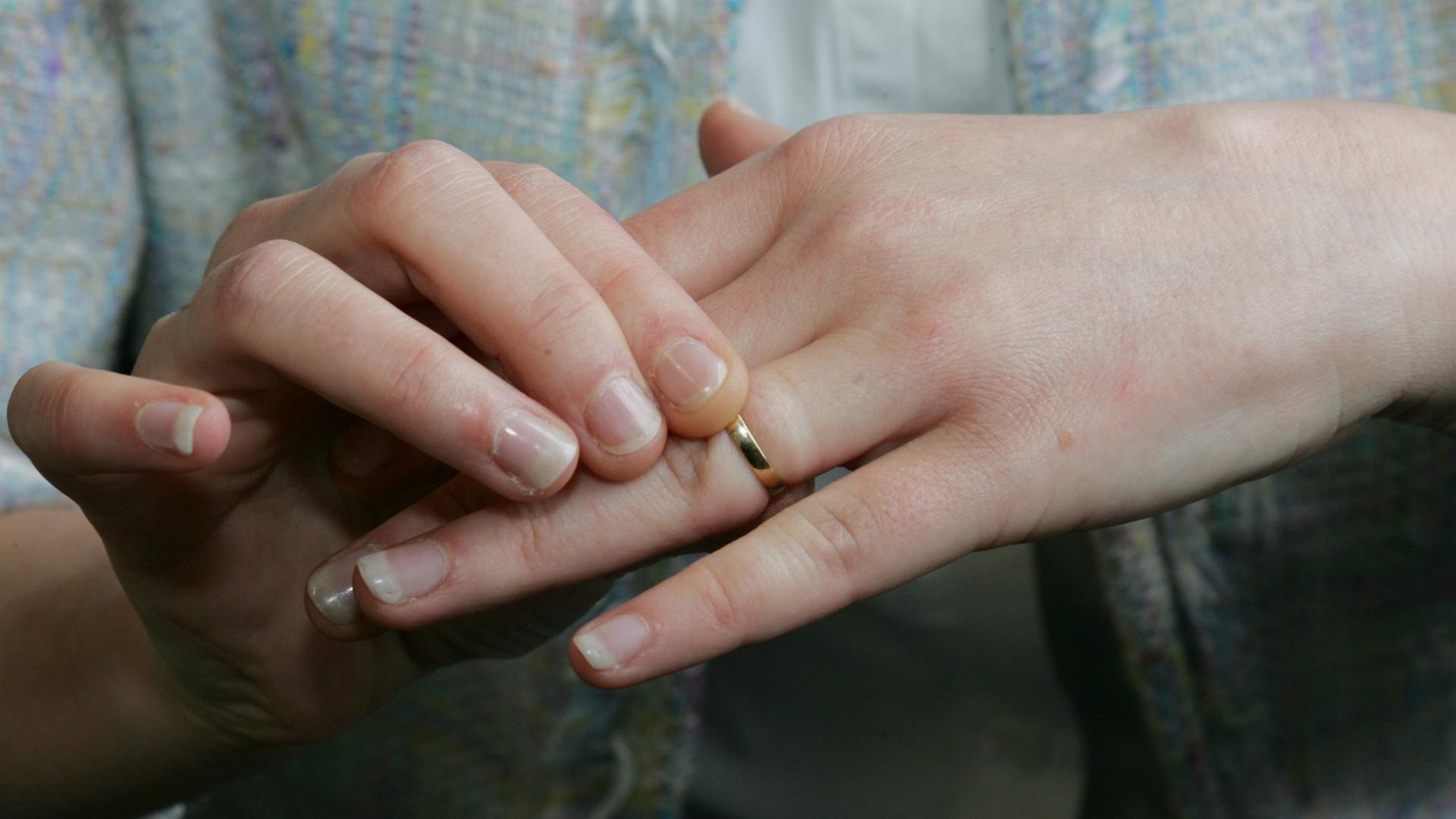 Eine Frau zieht ihren Ehering vom Finger.