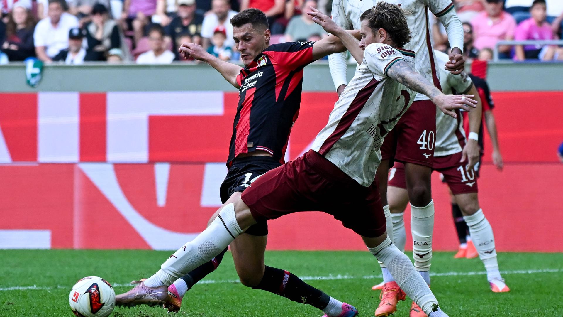 Leverkusens Stürmer Patrick Schick kämpft mit seinem Augsburger Gegenspieler Calvin Brackelmann um den Ball