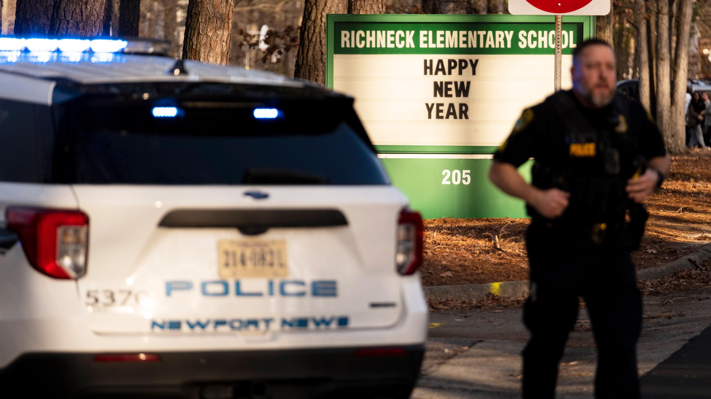 Links: Polizeiauto. Rechts: Polizist steht vor Schild der Richneck-Grundschule mit der Aufschrift "Happy New Year". Newport News, USA.
