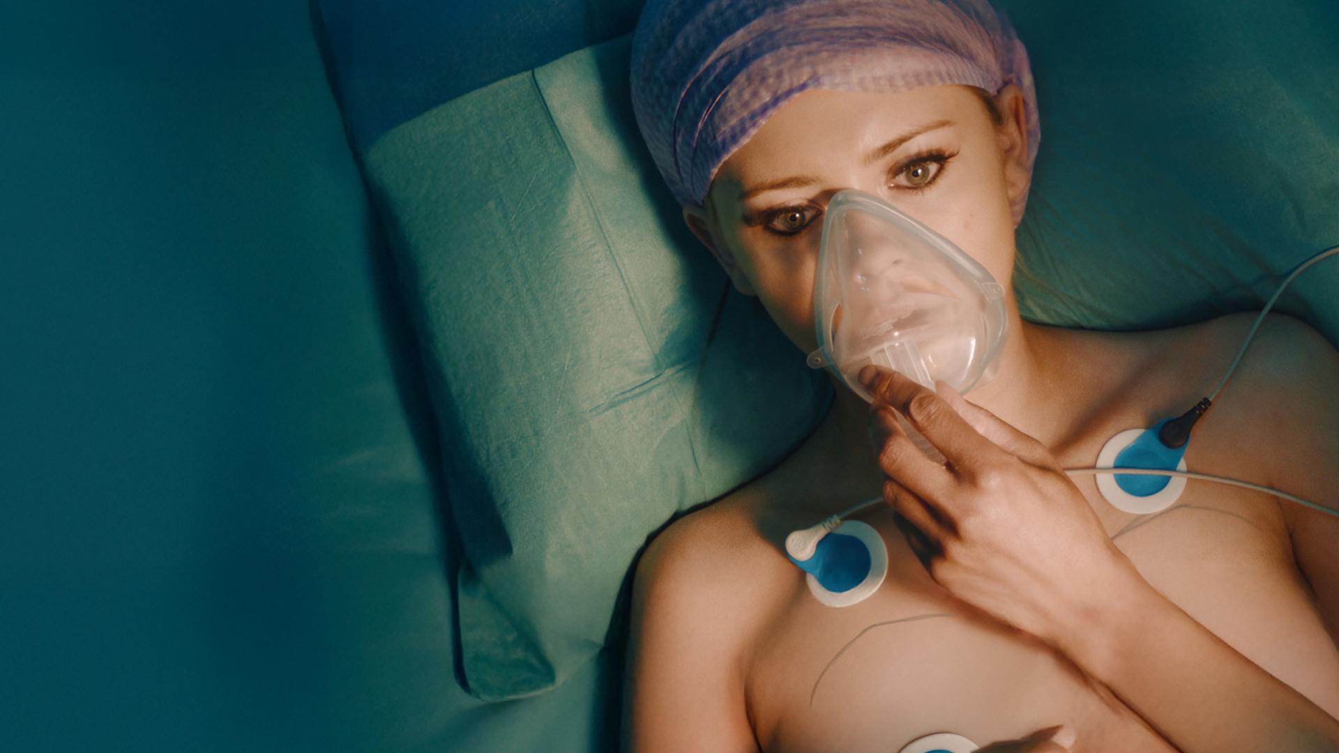 "Requiem for Selina - Schlaf mein kleines Püppchen": Blick von oben: Selina (Elli Rhiannon Müller Osborne) liegt im Operationsraum. Dabei liegt die Maske des Narkosesystems auf ihrem Gesicht.