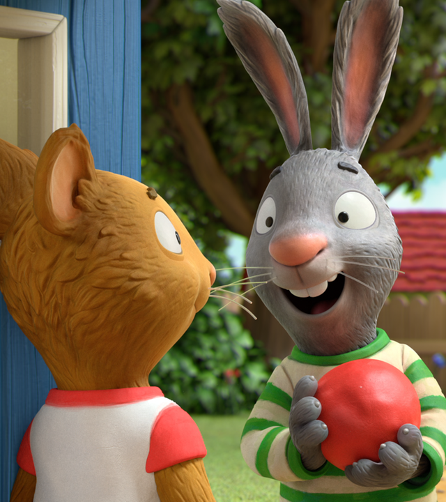 Pip hat einen roten Ball im Arm und spricht mit Posy. Beide stehen vor einem blauen Haus.