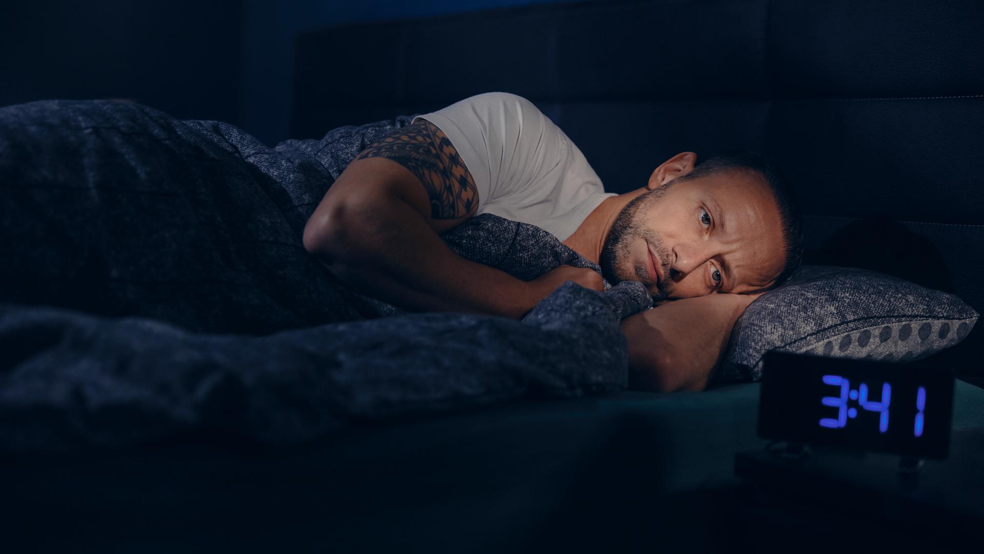 Waldemar liegt wach im Bett. Neben ihm steht ein Wecker, die Uhrzeit zeigt 3:41h nachts an. 