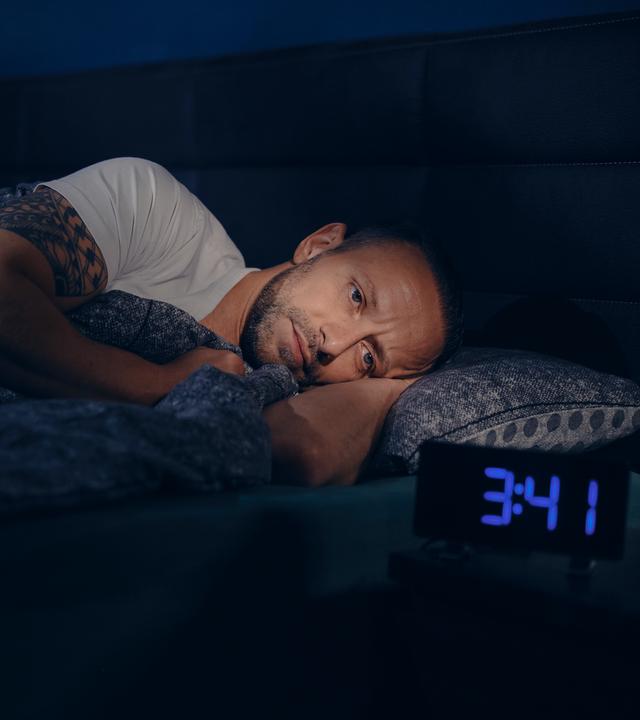 Waldemar liegt wach im Bett. Neben ihm steht ein Wecker, die Uhrzeit zeigt 3:41h nachts an. 