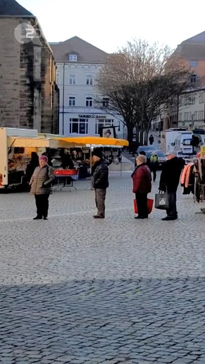 Einige Leute stehen Schlange auf einem Platz.