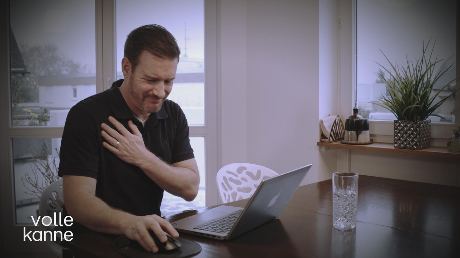 Mann fasst sich schmerzverzerrt an seine Schulter