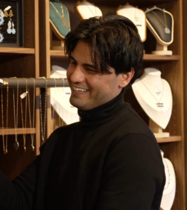 Hasib Azizi in seinem Schmuckgeschäft - im Hintergrund diverse Schmuckstücke in Regalen.