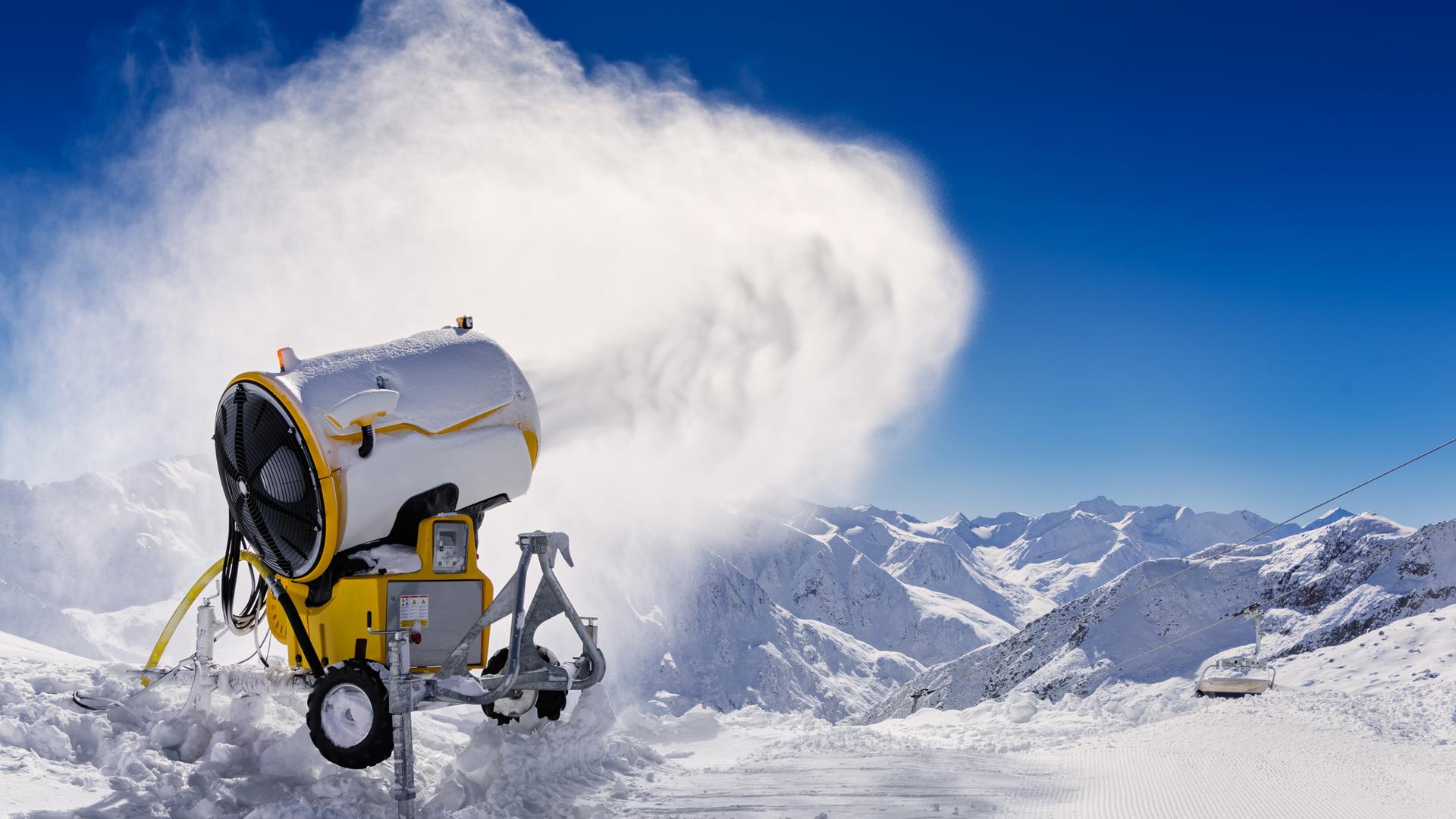Eine Schnee aussprühende Schneekanone vor strahlend blauem Himmel im Einsatz