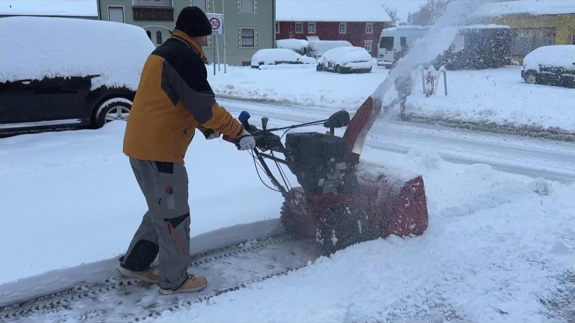 Ein Mann schippt Schnee mit einer Maschine