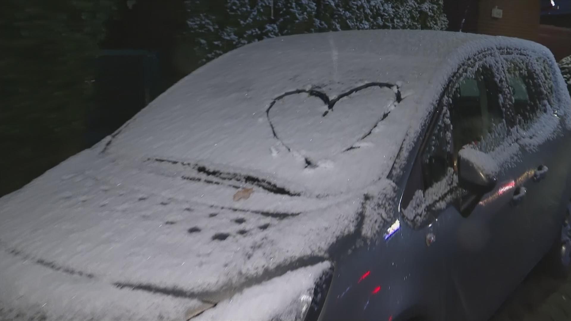Ein schneebedekctes Auto mit einem Herz auf der Scheibe.