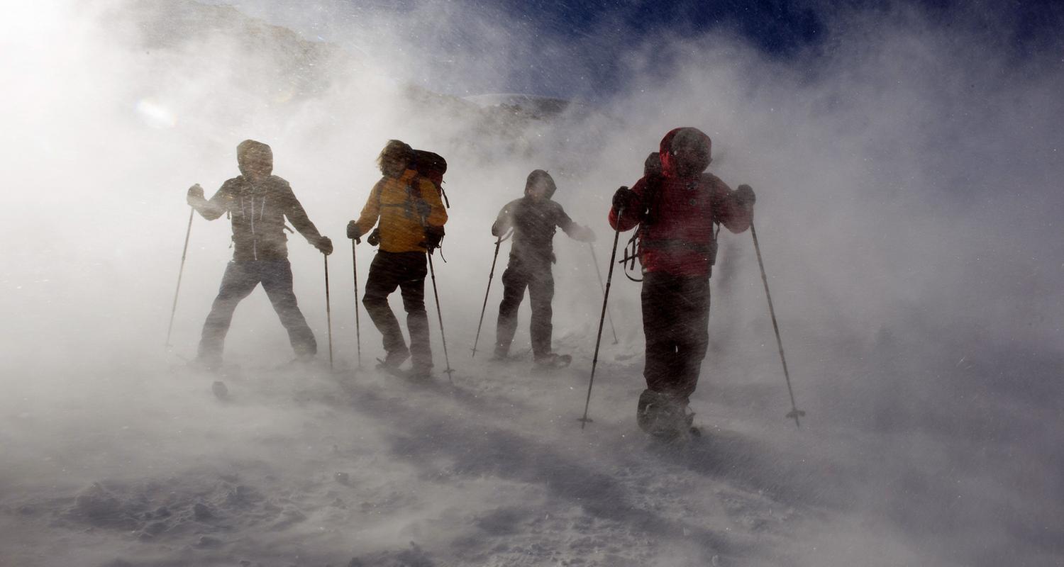 "Die Bergretter - Schneeblind (1)": Vier Männer auf Skiern stehen in einer Wolke aus Pulverschnee auf der Piste.