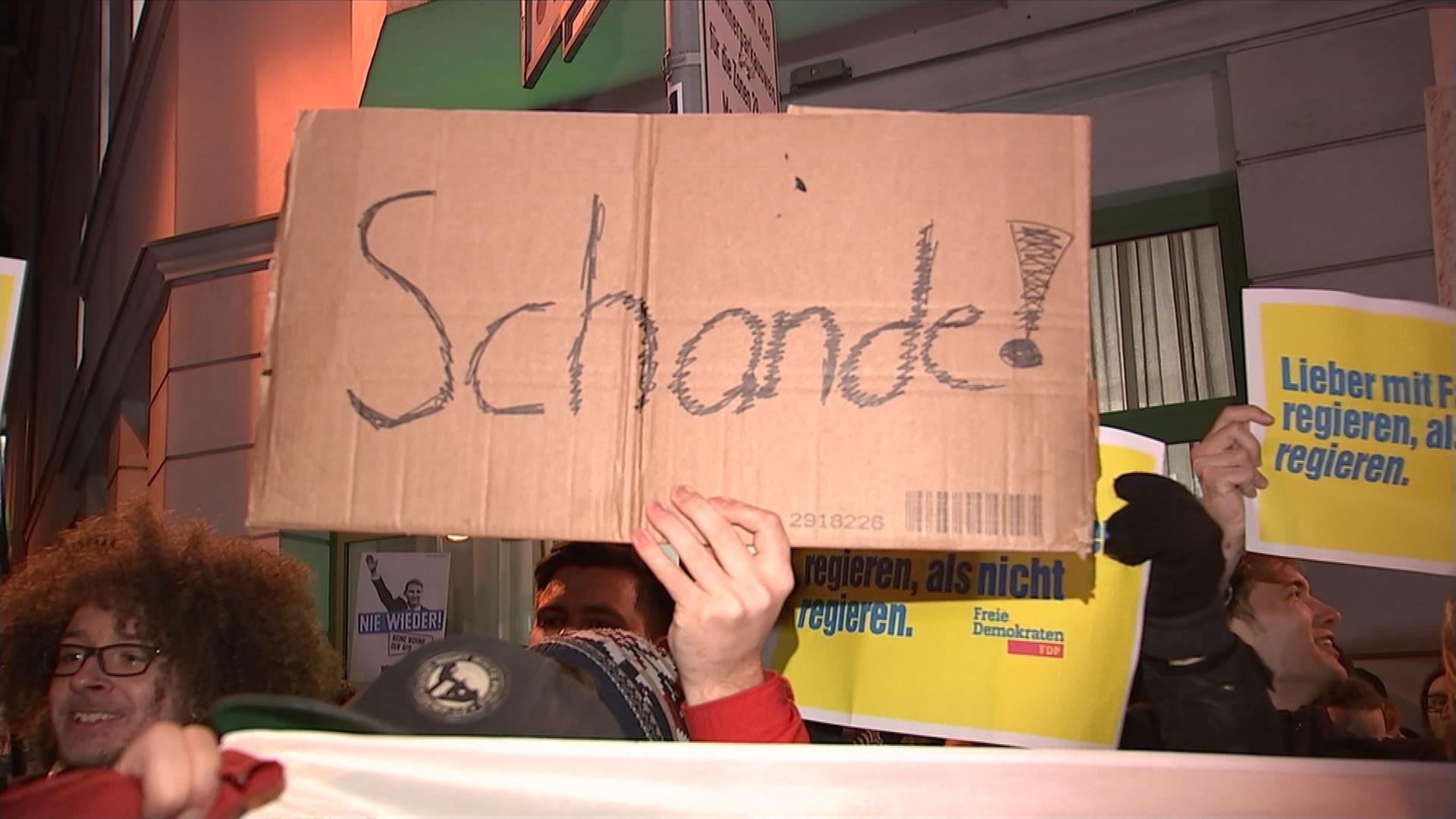menschen demonstrieren nach der wahl von kemmerich zum minsterpräsidenten, plakat mit der aufschrift schande 