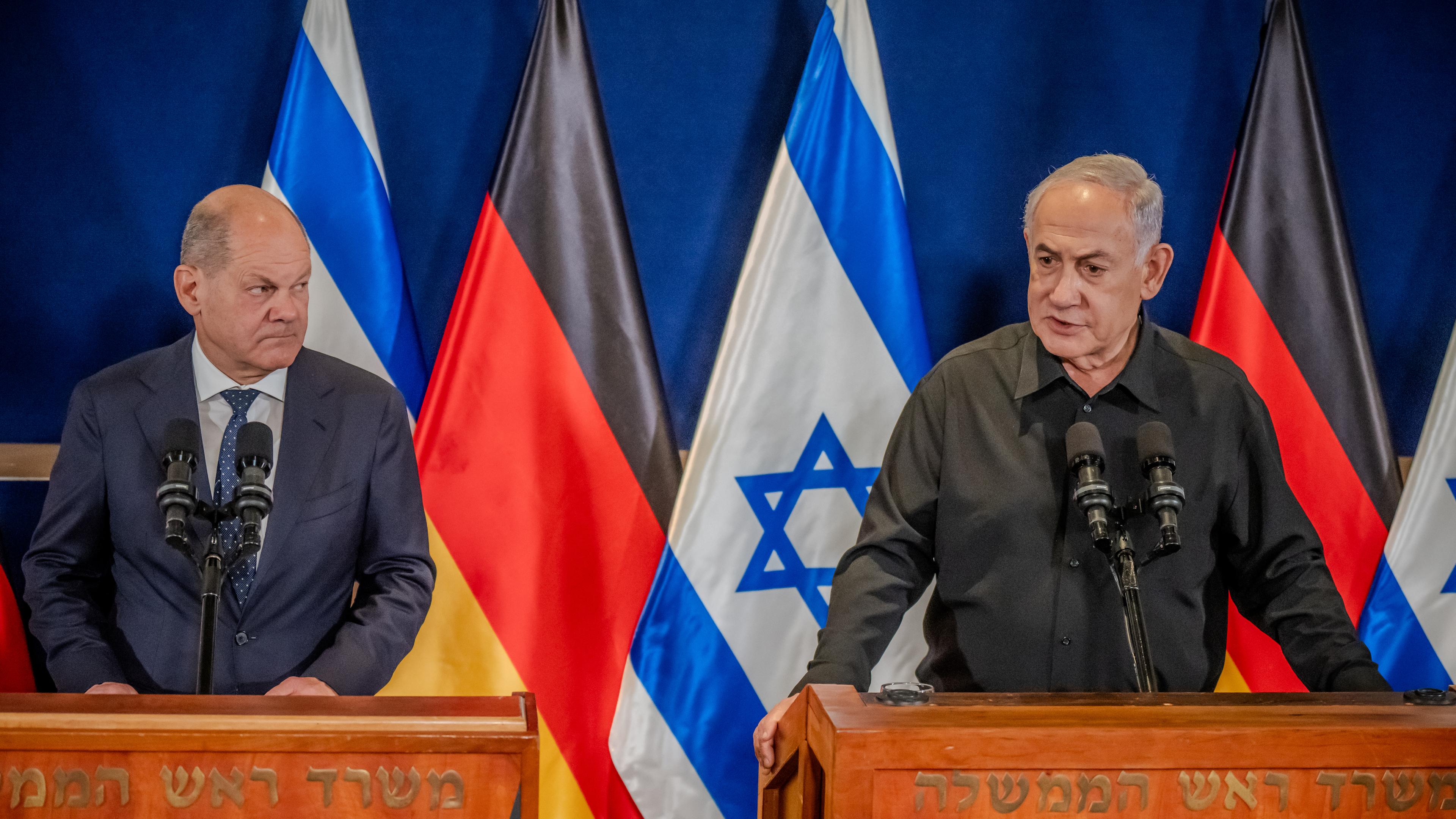 Bundeskanzler Scholz (links) und Ministerpräsident Netanjahu (rechts) an Rednerpulten - im Hintergrund Flaggen Deutschlands und Israels.