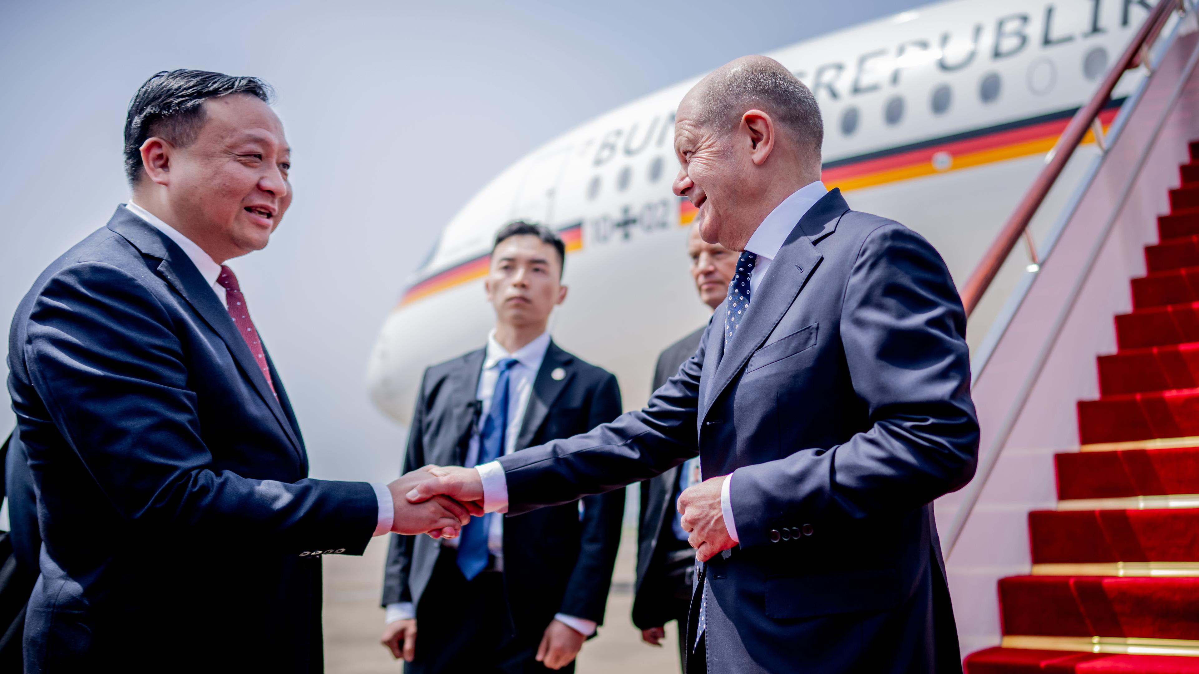 Bundeskanzler Olaf Scholz (SPD, r) wird am Flughafen Shanghai von Hua Yuan, Vizebürgermeister von Shanghai, begrüsst.