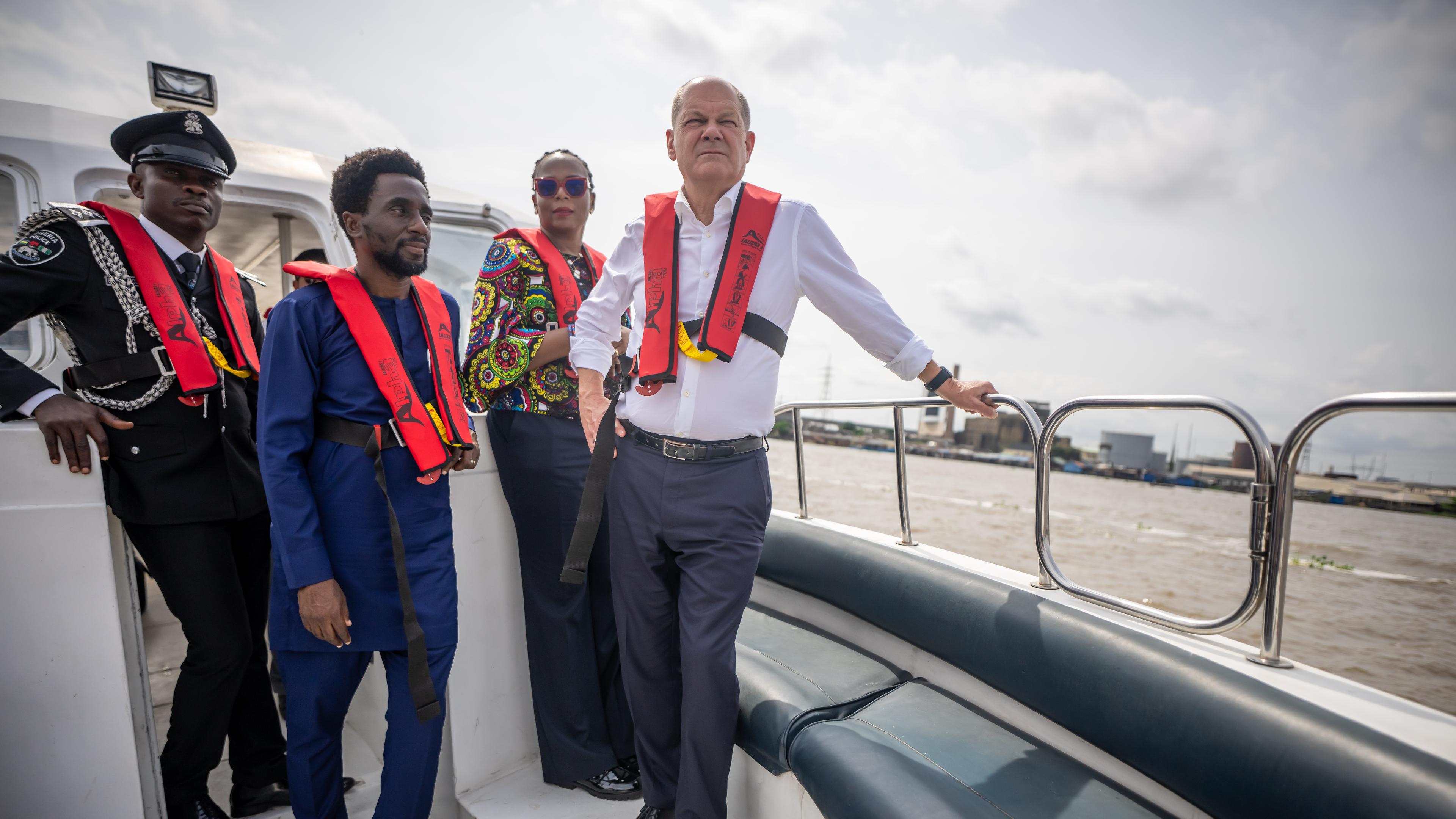 Bundeskanzler Scholz steht neben nigerianischen Vertretern bei einer Bootsfahrt in Lagos.