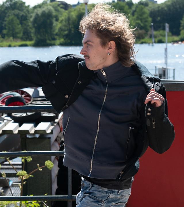 An der Außenalster: Kevin (Cedric Eich) ist im Begriff mit seiner rechten Faust Sebastian Matthiesen (Janek Rieke) zu schlagen, der verdutzt vor ihm steht.