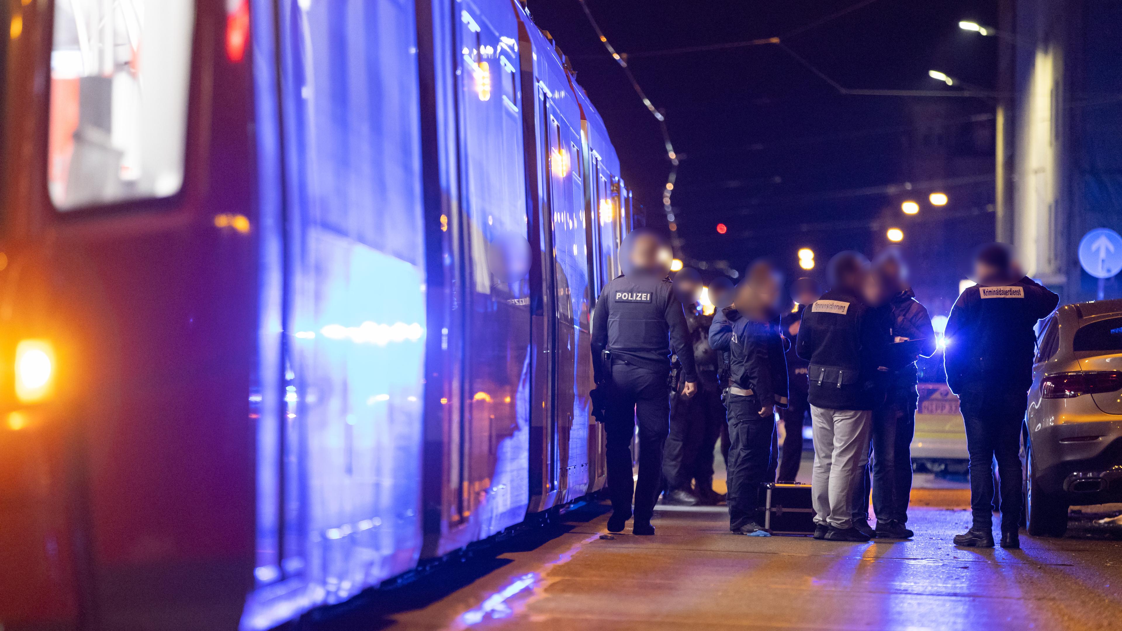 Polizisten stehen neben einer Straßenbahn in der nähe eines Tatorts in Nürnberg. 