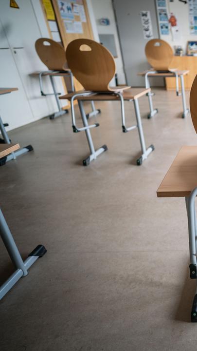 In einem Klassenraum stehen leere Tische und Stühle.