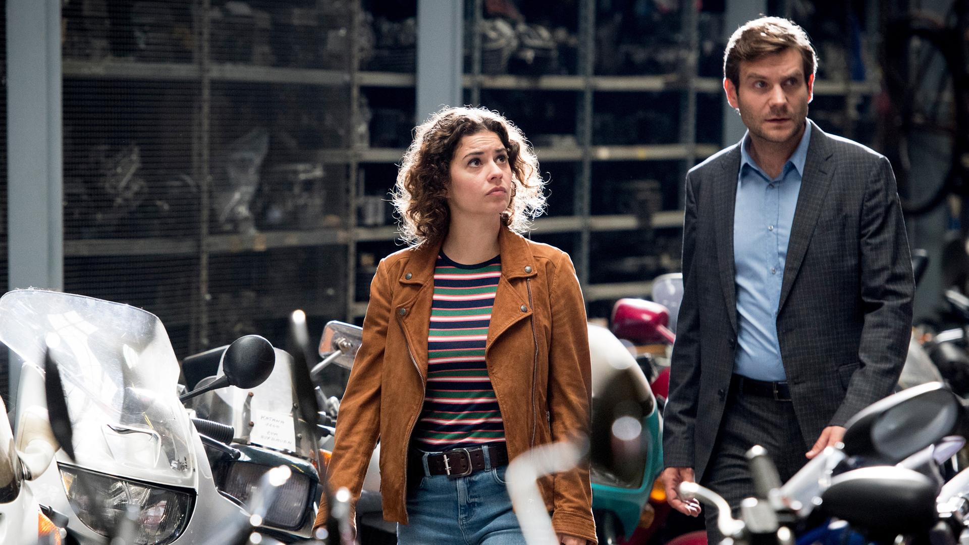 Lilly Funke und Jonas Fischer gehen durch eine Motorradwerkstatt