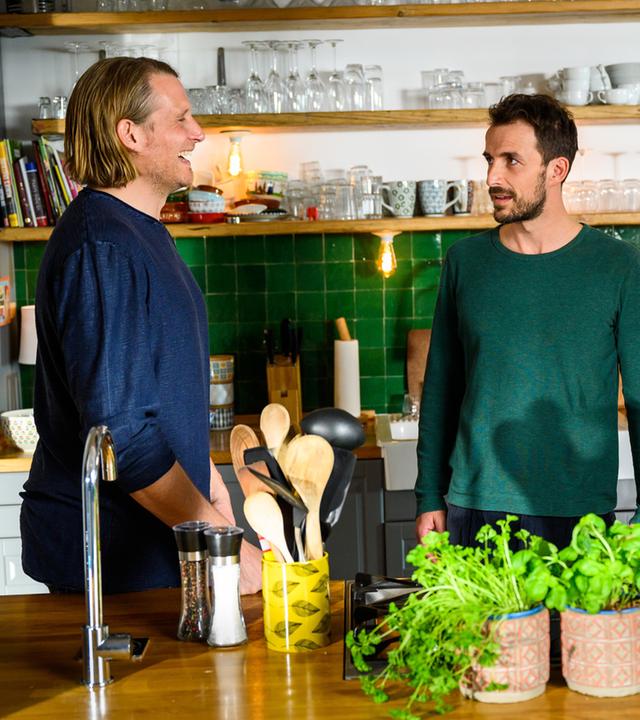 "Bettys Diagnose - Schuld und Familie": Oliver Weiss (Alexander Koll), Dr. Frank Stern (Max Alberti) und Betty Weiss (Annina Hellenthal) stehen bei ihr in der Küche. Oliver lacht herzlich, während Frank Stern ihn skeptisch anschaut und Betty Oliver anlächelt.