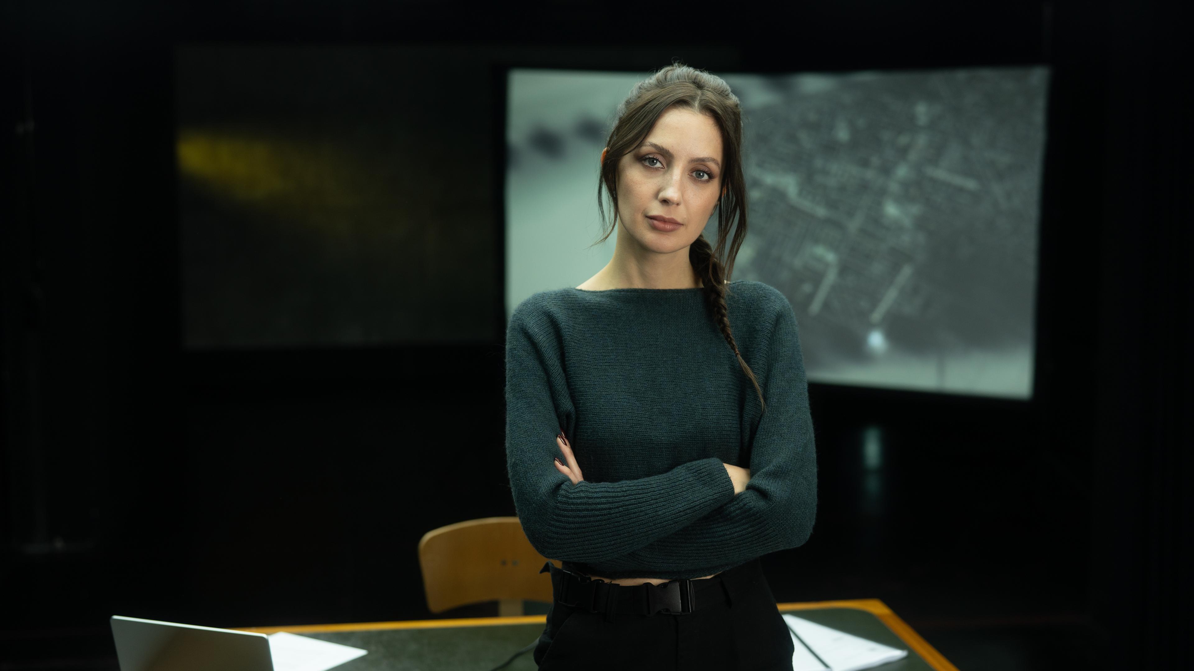  Paulina Krasa steht vor einem Schreibtisch in einem dunklen Studio.