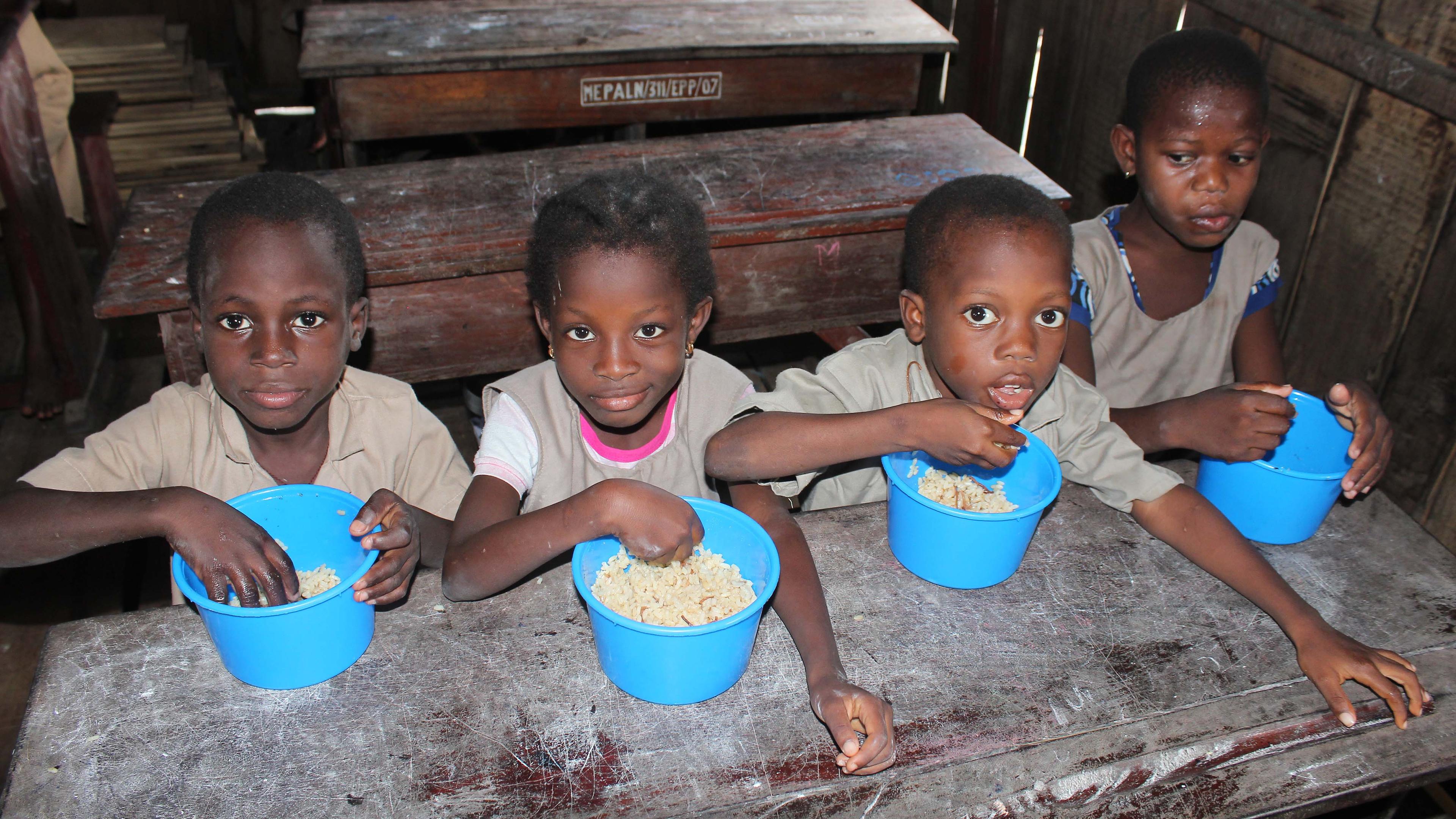 Schüler essen Reis zum Mittagessen in einer Grundschule in Benin.