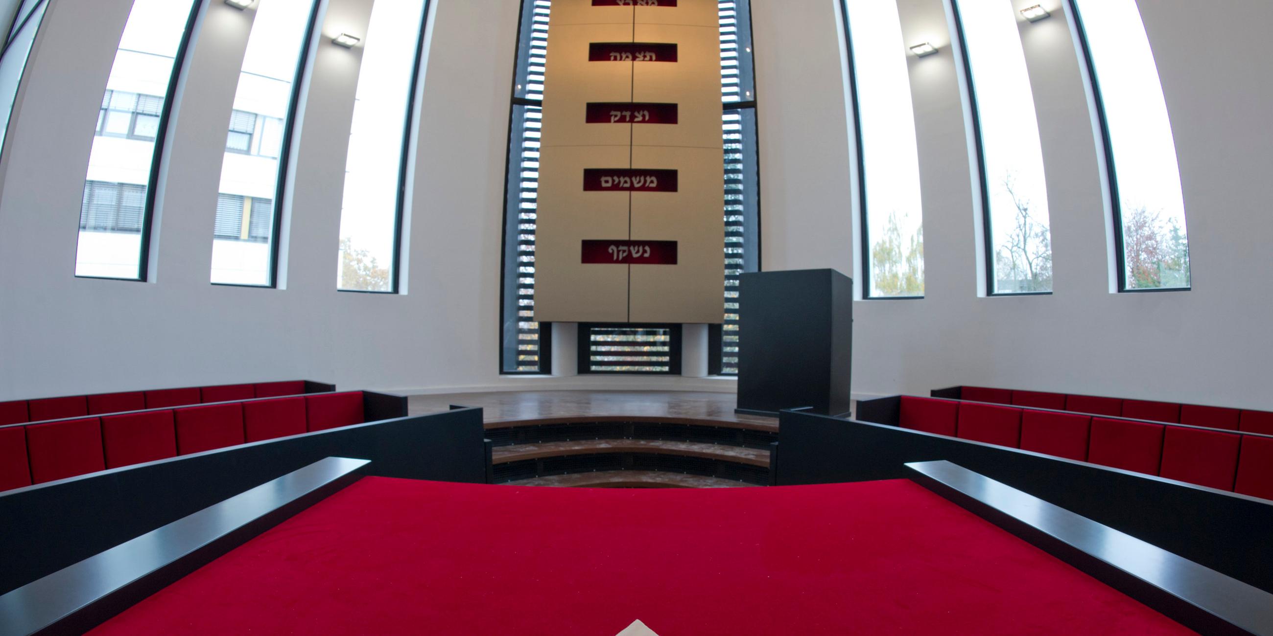 Ein Teil der Synagoge in Speyer ist abgebildet mit rotem Teppich und großen Fenstern.