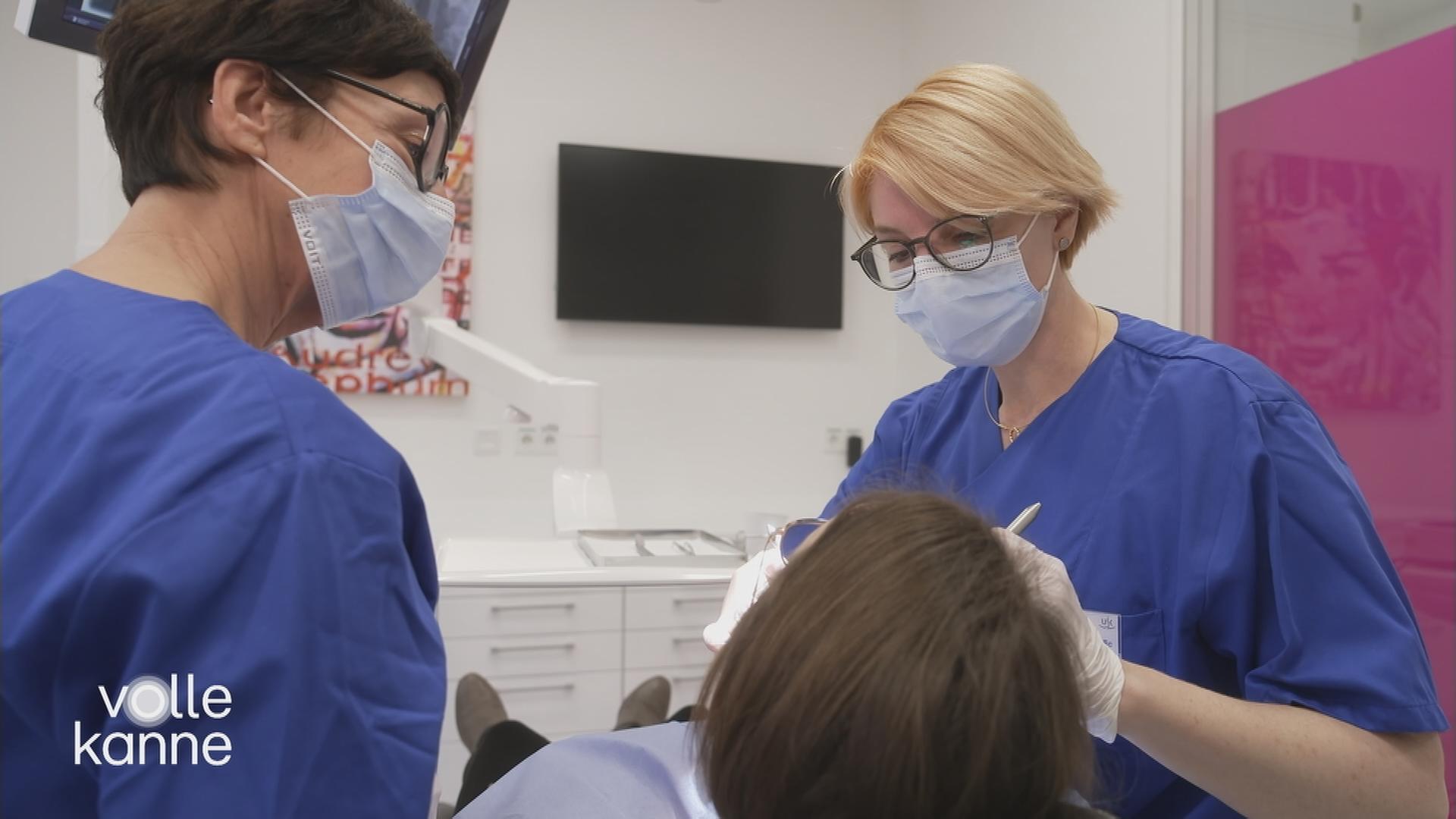Eine Frau (von hinten zu sehen) auf einem Stuhl in Behandlung beim Zahnarzt.