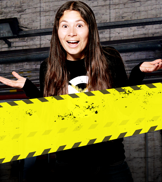 Checkpoint: Maja hängt mit Schutzhelm und Klettergurt an einem Seil und schaut lachend in die Kamera. 