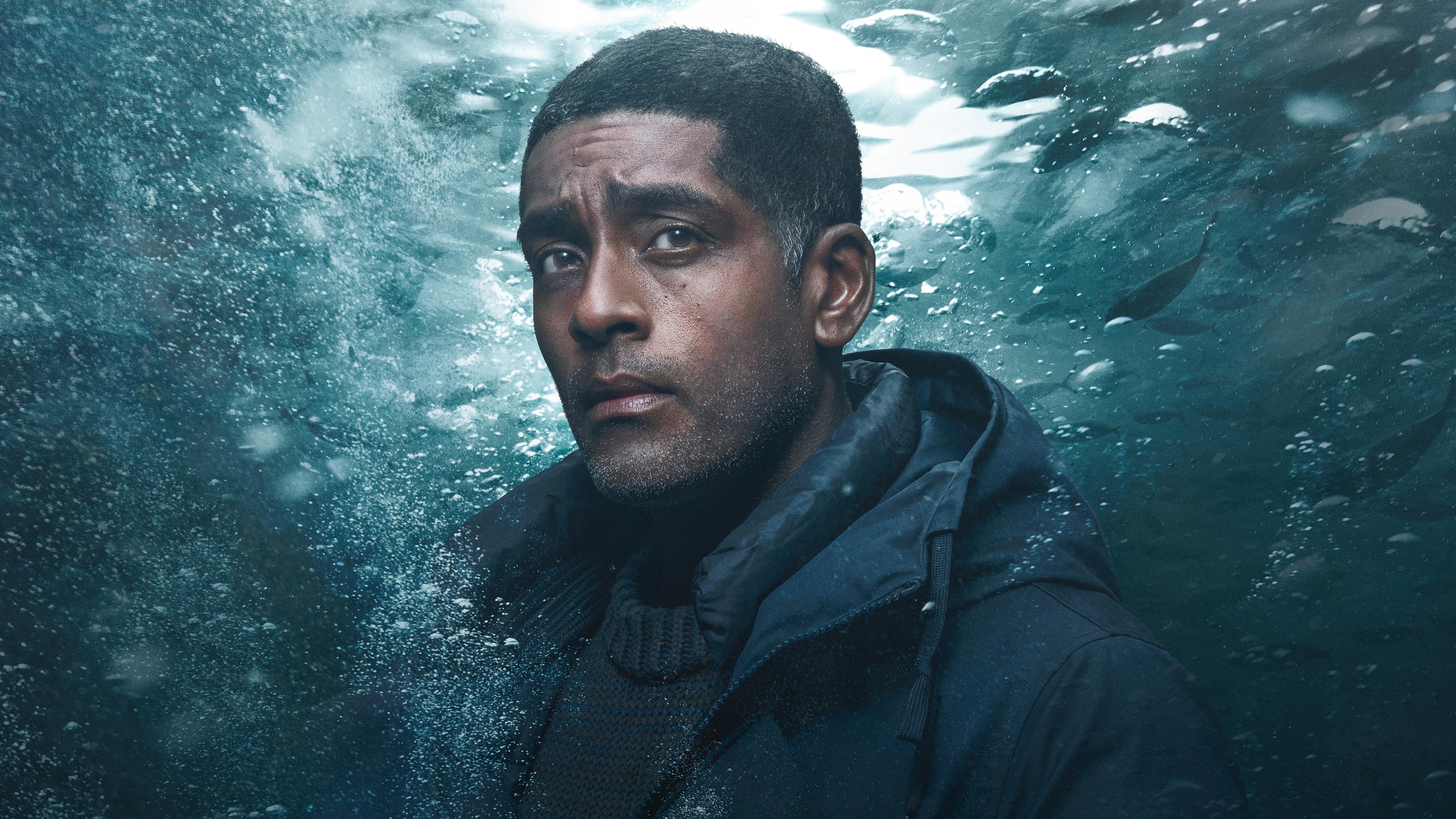 Dr. Sigur Johanson (Alexander Karim) vor einem Unter-Wasser-Hintergrund.