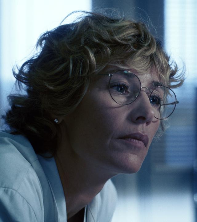 Dr. Cécile Roche (Cécile de France) sitzt nachdenklich in einem Büro, sie trägt einen weißen Kittel. 