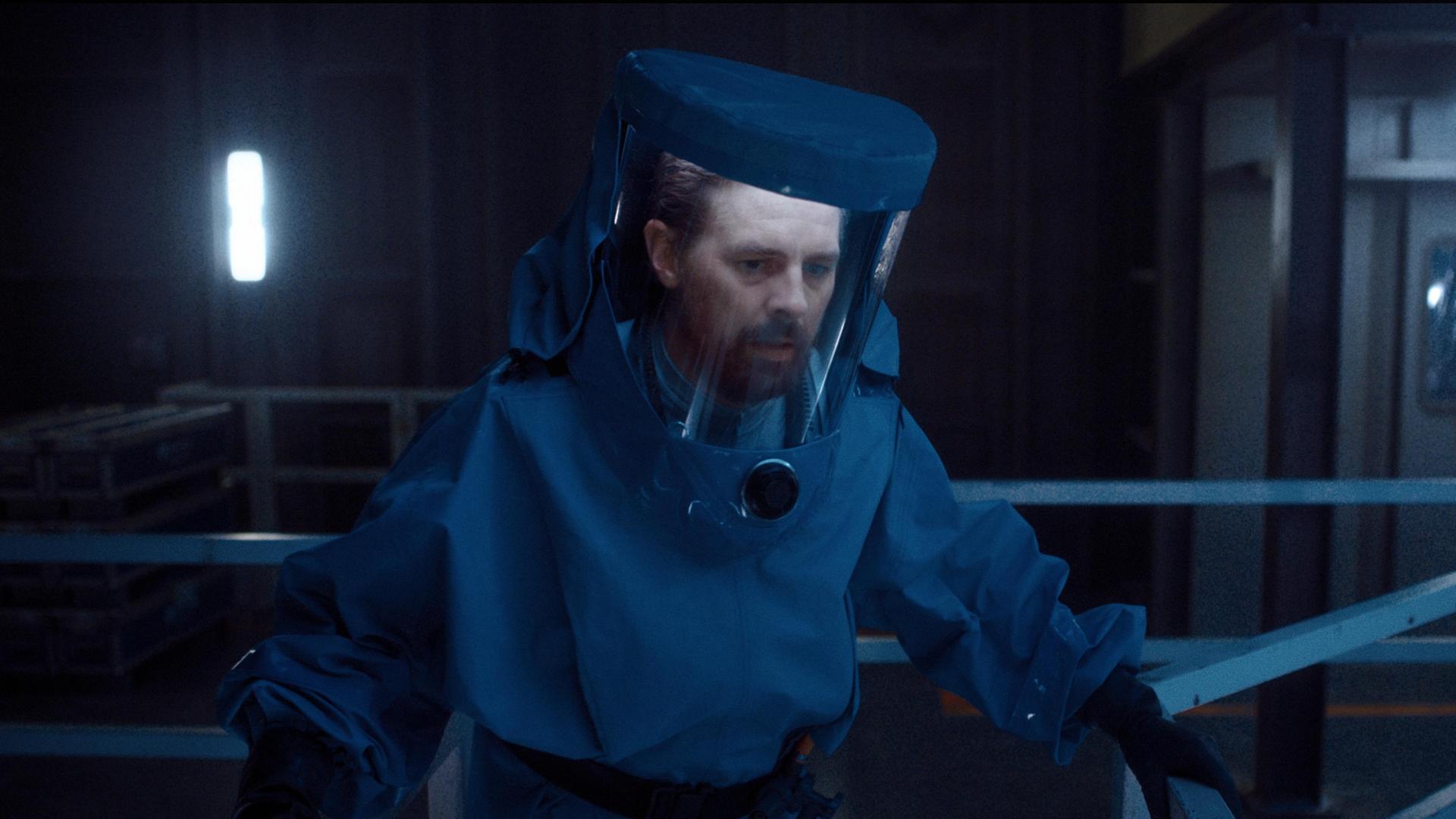 Tauchrobotik-Experte Luther Roscovitz (Klaas Heufer-Umlauf) trägt einen Schutzanzug. Sein Blick ist besorgt.