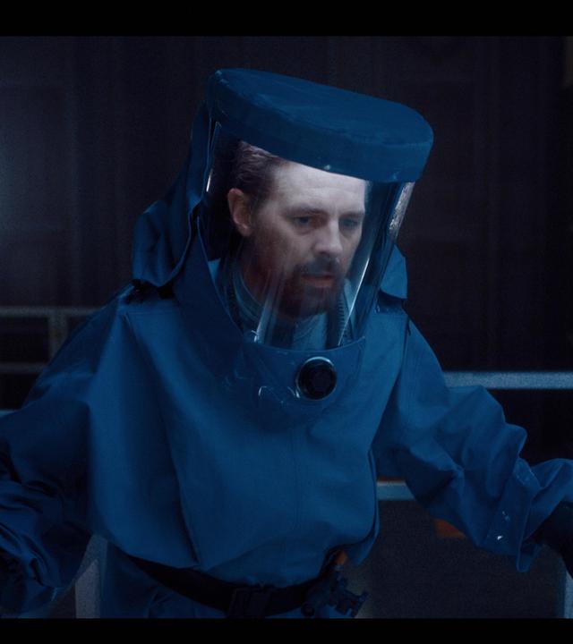Tauchrobotik-Experte Luther Roscovitz (Klaas Heufer-Umlauf) trägt einen Schutzanzug. Sein Blick ist besorgt.