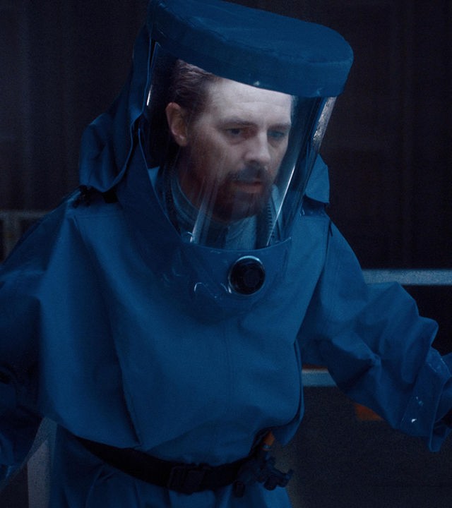 Tauchrobotik-Experte Luther Roscovitz (Klaas Heufer-Umlauf) trägt einen Schutzanzug. Sein Blick ist besorgt.