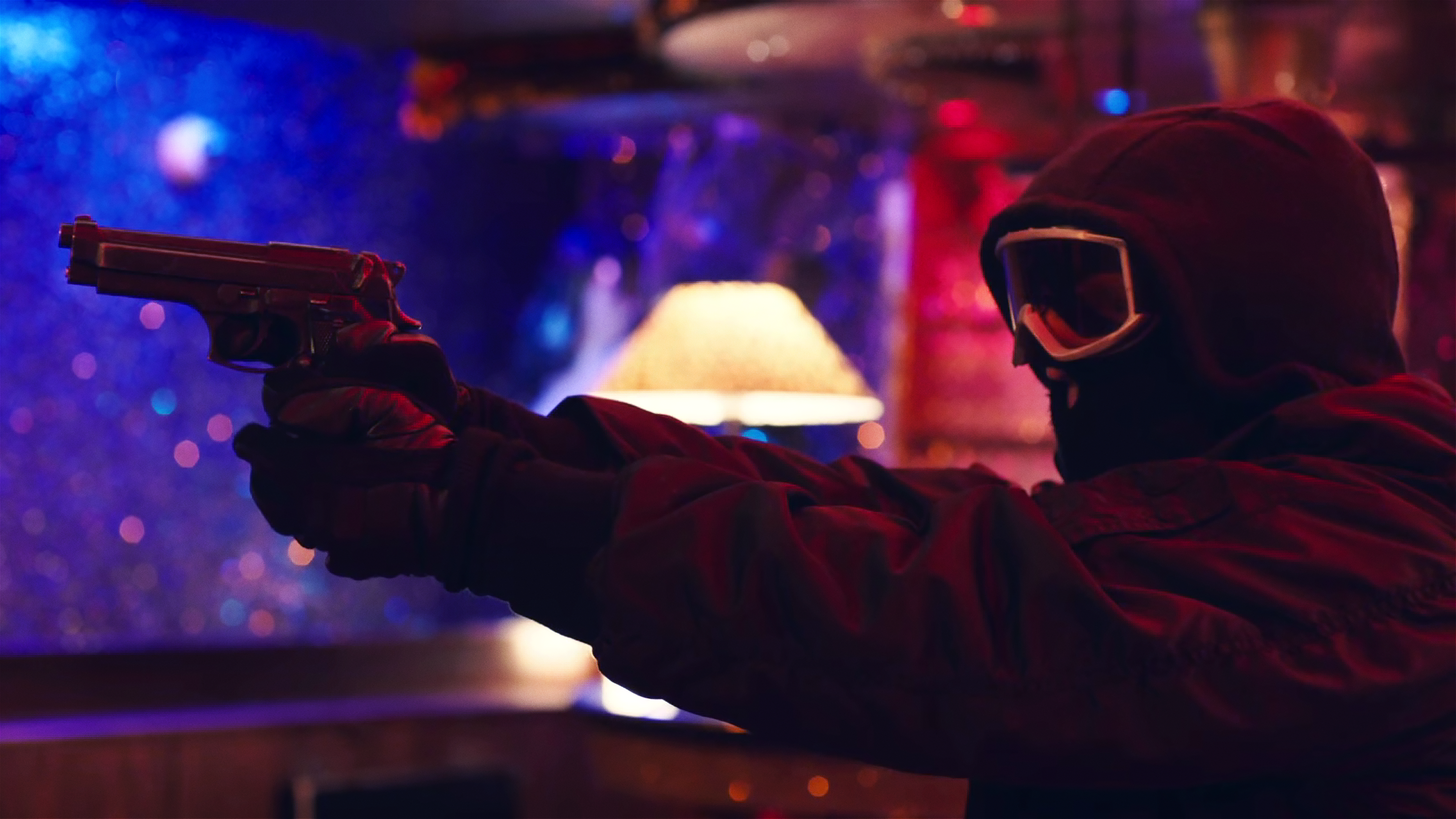In einem Nachtclub zielt eine maskierte Person in Mütze, Skibrille und Handschuhen mit einer Waffe. 