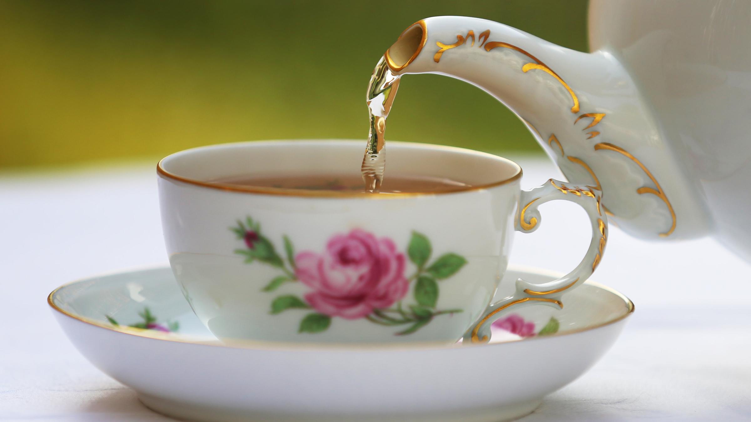 Schwarzer Tee wird in eine Teetasse eingeschenkt.