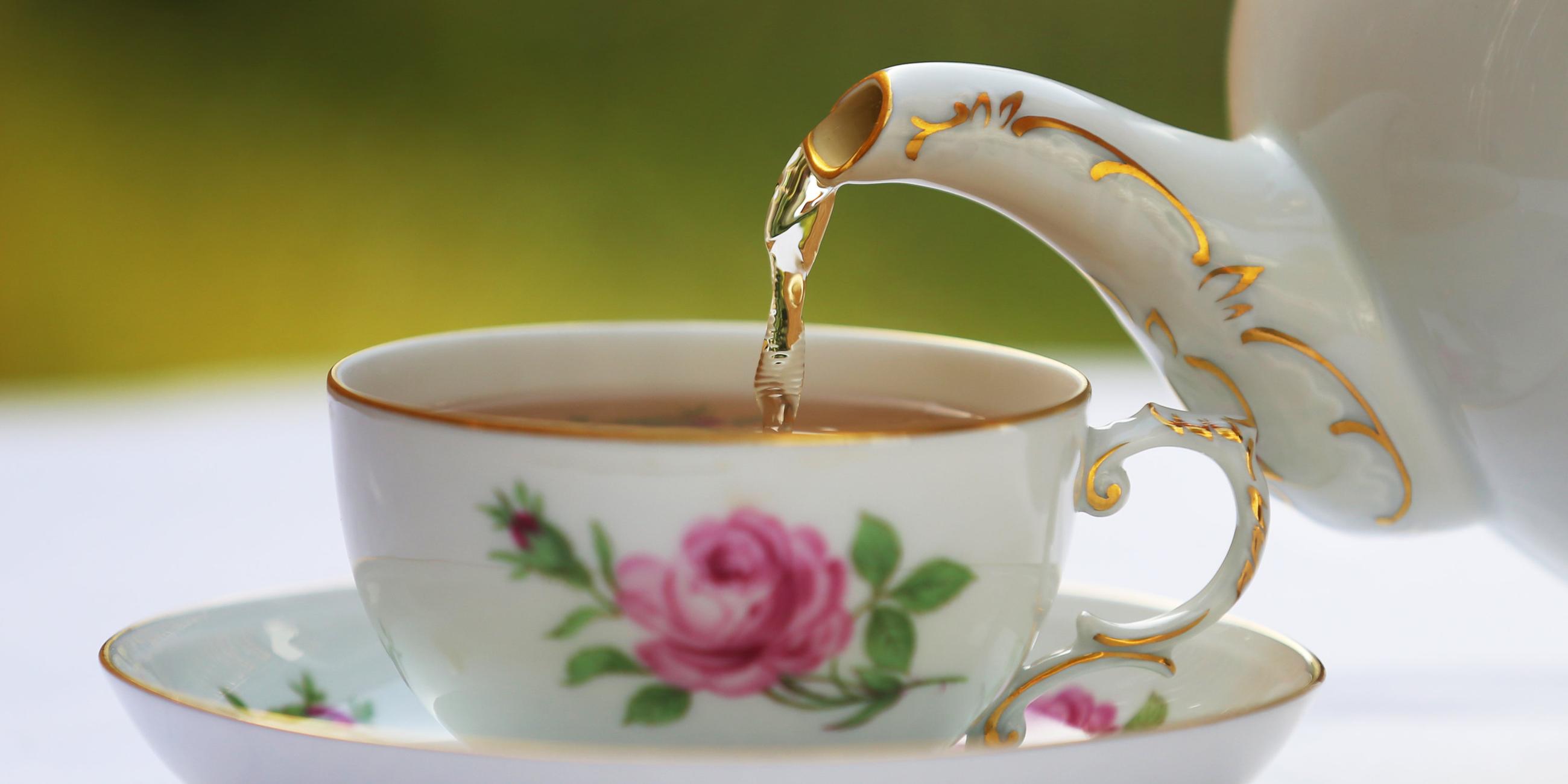 Schwarzer Tee wird in eine Teetasse eingeschenkt.